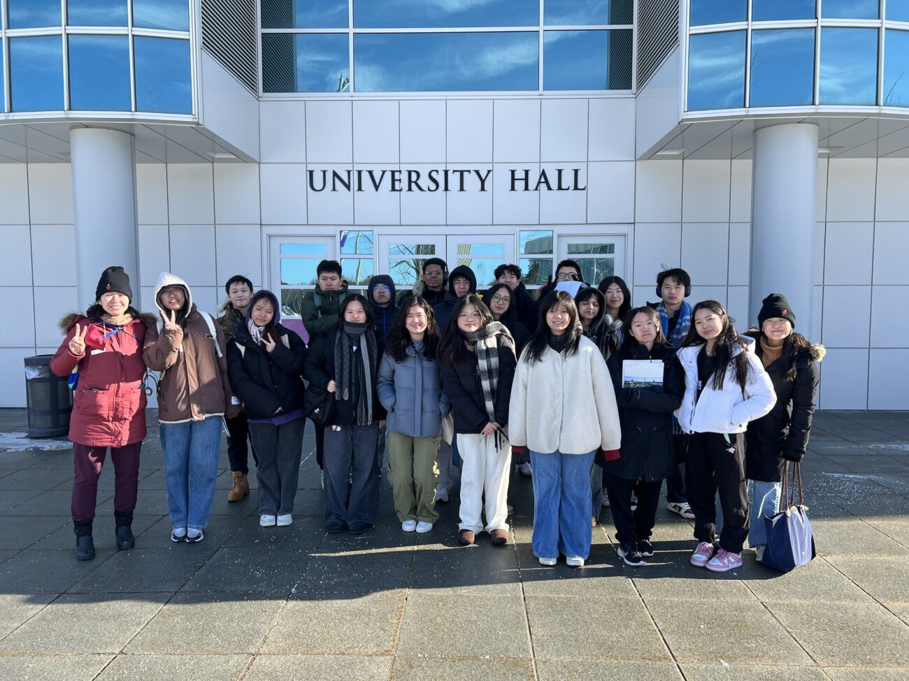 Photo of Apex for Youth students standing in front of a SUNY Albany campus sign, smiling and posing for a group picture